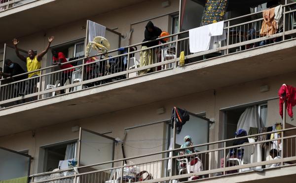 Migrants wave from the their balconies in Kranidi, southern Greece, on Tuesday. Authorities confirmed a high number of COVID-19 infections at the site. Migrants wave from the their balconies in Kranidi, southern Greece, on Tuesday. Authorities confirmed a high number of COVID-19 infections at the site.