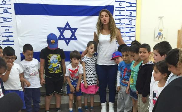 A kindergarten teacher in Jerusalem stands with students as they listen to sirens that played nationwide on Thursday to commemorate Holocaust Remembrance Day. This year, a new national Holocaust curriculum is being fully implemented in kindergarten. A kindergarten teacher in Jerusalem stands with students as they listen to sirens that played nationwide on Thursday to commemorate Holocaust Remembrance Day. This year, a new national Holocaust curriculum is being fully implemented in kindergarten.