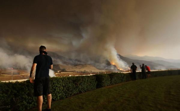 Resident Moe Blythe watches the Holy Fire burn near homes on August 9, 2018 in Corona, California. Resident Moe Blythe watches the Holy Fire burn near homes on August 9, 2018 in Corona, California.