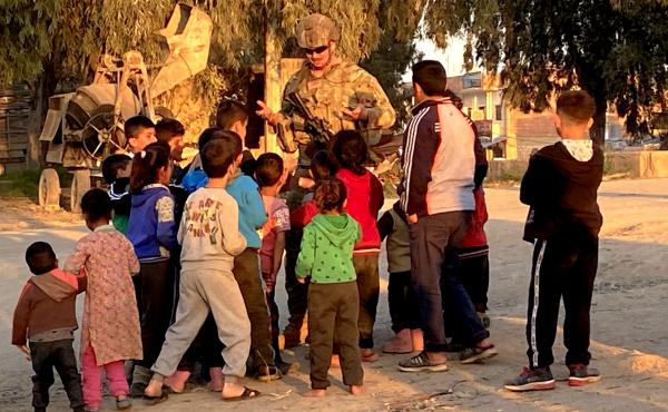 A soldier holds his hands up trying to tell the children he is out of lollipops. Kurdish refugees are streaming in to Tal Tamr and nearby villages in Syria. A soldier holds his hands up trying to tell the children he is out of lollipops. Kurdish refugees are streaming in to Tal Tamr and nearby villages in Syria.