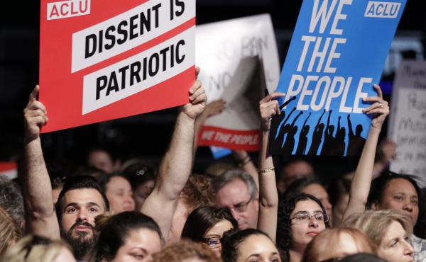 Protesters hold up signs during a meeting called "The Resistance Training" hosted by the American Civil Liberties Union in March. Protesters hold up signs during a meeting called "The Resistance Training" hosted by the American Civil Liberties Union in March.