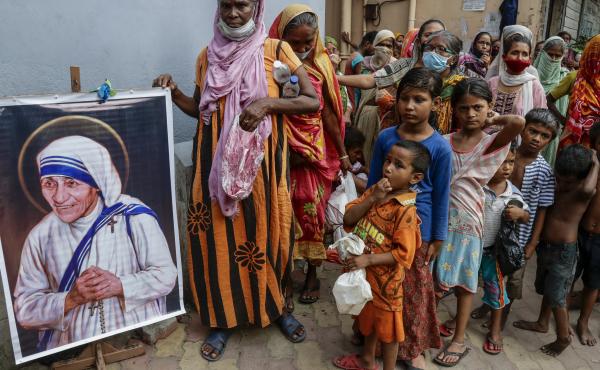 Homeless people gather beside a portrait of Saint Teresa, the founder of the Missionaries of Charity, to collect free food outside the order's headquarters in Kolkata, India, in August. Homeless people gather beside a portrait of Saint Teresa, the founder of the Missionaries of Charity, to collect free food outside the order's headquarters in Kolkata, India, in August.