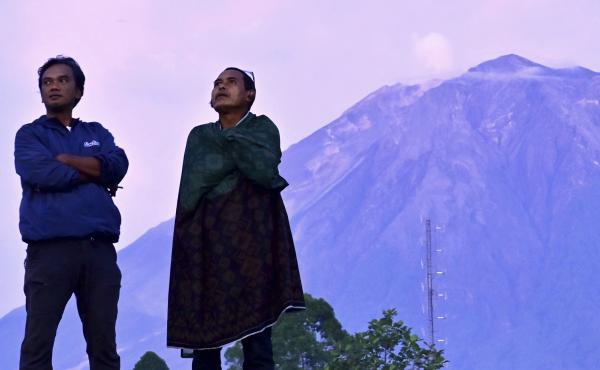 Indonesian villagers stand with Mount Semeru in the background on Saturday. Indonesian authorities raised the alert level for the highest volcano on Java island, saying it could blow up again after a sudden eruption earlier this month that killed dozens o Indonesian villagers stand with Mount Semeru in the background on Saturday. Indonesian authorities raised the alert level for the highest volcano on Java island, saying it could blow up again after a sudden eruption earlier this month that killed dozens o