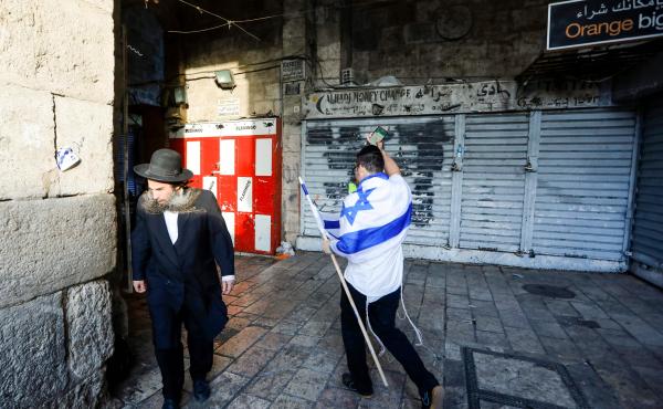 An Israeli draped in the national flag walks past an ultra-Orthodox Jewish man in Jerusalem's Old City on May 13, as Israelis marked Jerusalem Day. An Israeli draped in the national flag walks past an ultra-Orthodox Jewish man in Jerusalem's Old City on May 13, as Israelis marked Jerusalem Day.