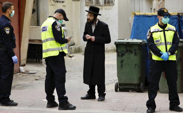 An ultra-Orthodox Jewish man is questioned by an Israeli police officer as part of the government's measures to stop the spread of the coronavirus, in the Orthodox city of Bnei Brak, a suburb of Tel Aviv, Israel, on Tuesday. An ultra-Orthodox Jewish man is questioned by an Israeli police officer as part of the government's measures to stop the spread of the coronavirus, in the Orthodox city of Bnei Brak, a suburb of Tel Aviv, Israel, on Tuesday.