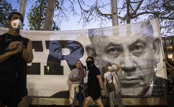 Israeli Prime Minister Benjamin Netanyahu, shown here on a banner at an anti-corruption rally on Sunday, has reached a deal for a unity government with his rival Benny Gantz. Israeli Prime Minister Benjamin Netanyahu, shown here on a banner at an anti-corruption rally on Sunday, has reached a deal for a unity government with his rival Benny Gantz.