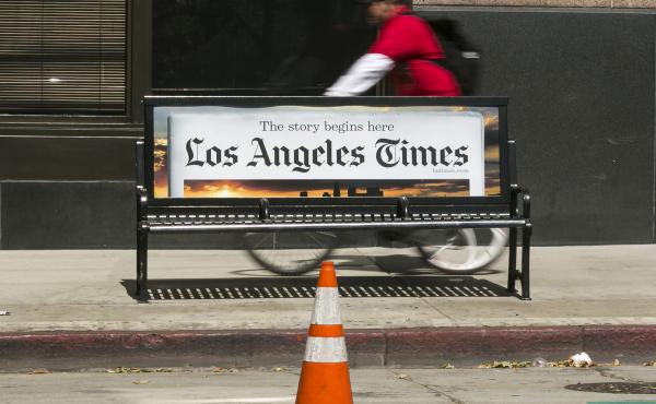 A cyclist rides on the sidewalk past a Los Angeles Times advertisement in downtown Los Angeles. The newspaper is being sued by employees alleging pay discrimination. A cyclist rides on the sidewalk past a Los Angeles Times advertisement in downtown Los Angeles. The newspaper is being sued by employees alleging pay discrimination.