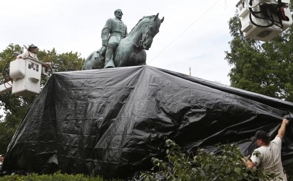 City workers drape a tarp over the statue of Confederate General Robert E. Lee in Charlottesville, Va. on Aug. 23, 2017. City workers drape a tarp over the statue of Confederate General Robert E. Lee in Charlottesville, Va. on Aug. 23, 2017.