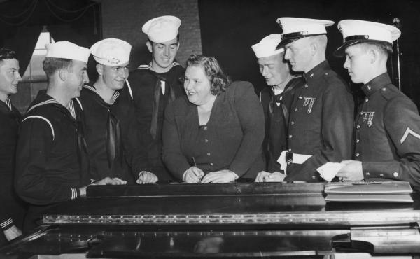 Singer Kate Smith, signing autographs for a group of American sailors c. 1938. Singer Kate Smith, signing autographs for a group of American sailors c. 1938.