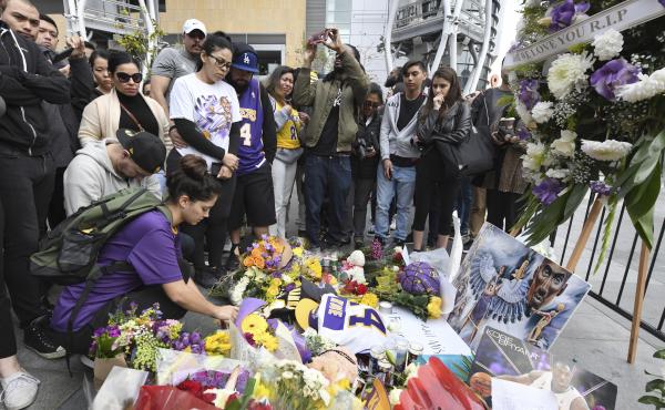 Valerie Samano, left, places flowers at a memorial near the Staples Center in Los Angeles, after the death of Laker legend Kobe Bryant on Sunday. Valerie Samano, left, places flowers at a memorial near the Staples Center in Los Angeles, after the death of Laker legend Kobe Bryant on Sunday.