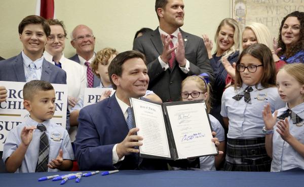 Florida Gov. Ron DeSantis displays the signed Parental Rights in Education, the so-called "Don't Say Gay" bill, flanked by elementary school students during a news conference on Monday at Classical Preparatory school in Shady Hills, Fla. Florida Gov. Ron DeSantis displays the signed Parental Rights in Education, the so-called "Don't Say Gay" bill, flanked by elementary school students during a news conference on Monday at Classical Preparatory school in Shady Hills, Fla.