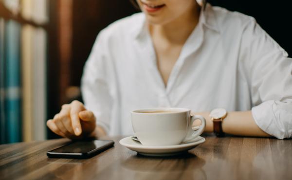 A young woman sits in cafe while text messaging on her smartphone. A young woman sits in cafe while text messaging on her smartphone.