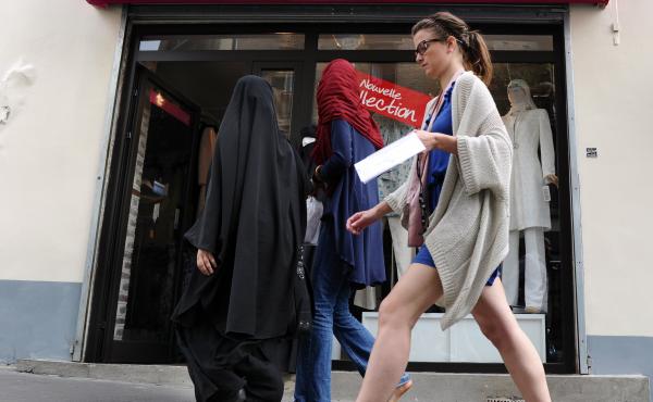 Three women, two of them partially veiled, walk past a hijabs shop in Paris. The wearing of the veil has been a serious point of contention in France, with the government banning its use in public schools and the wearing of face-covering garments, includi Three women, two of them partially veiled, walk past a hijabs shop in Paris. The wearing of the veil has been a serious point of contention in France, with the government banning its use in public schools and the wearing of face-covering garments, includi
