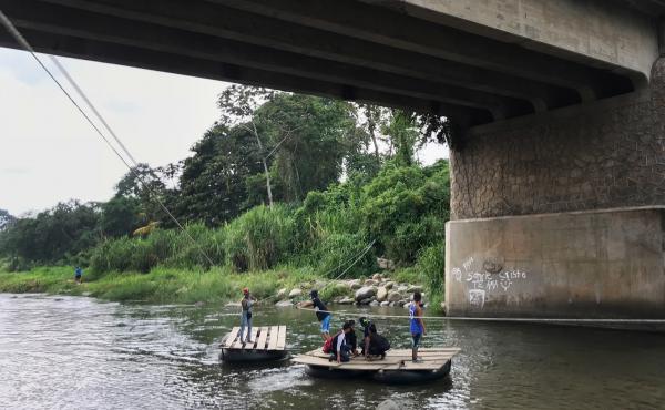Migrants and day laborers cross the Suchiate River, which divides Mexico and Guatemala. The crossing happens despite immigration officials working on the bridge above. Migrants and day laborers cross the Suchiate River, which divides Mexico and Guatemala. The crossing happens despite immigration officials working on the bridge above.