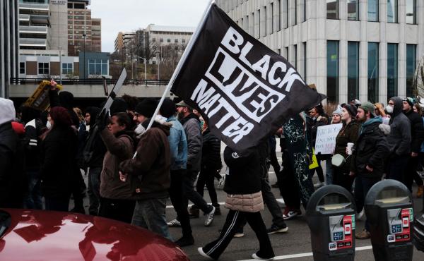 Protesters hold a Black Lives Matter flag as they march for Patrick Lyoya, a Black man who was fatally shot by a police officer, in downtown Grand Rapids, Mich. Protesters hold a Black Lives Matter flag as they march for Patrick Lyoya, a Black man who was fatally shot by a police officer, in downtown Grand Rapids, Mich.