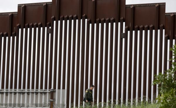 A Border Patrol agent walks along a border wall separating Tijuana, Mexico, from San Diego, in March 2020. A Border Patrol agent walks along a border wall separating Tijuana, Mexico, from San Diego, in March 2020.