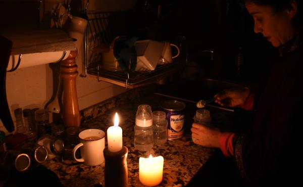 A woman prepares milk bottles Sunday using candles at her home in Montevideo during a power cut. A woman prepares milk bottles Sunday using candles at her home in Montevideo during a power cut.