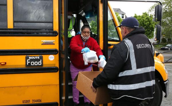 Nutritionist Shaunté Fields (center) and bus driver Treva White (behind Fields, on the bus) deliver meals to children and their families in Seattle. When schools closed because of COVID-19, Seattle Public Schools began distributing breakfast and lunch to Nutritionist Shaunté Fields (center) and bus driver Treva White (behind Fields, on the bus) deliver meals to children and their families in Seattle. When schools closed because of COVID-19, Seattle Public Schools began distributing breakfast and lunch to