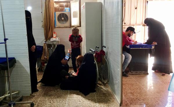 Women sit on the floor as they wait in a clinic at the al-Hol detention camp. Women sit on the floor as they wait in a clinic at the al-Hol detention camp.