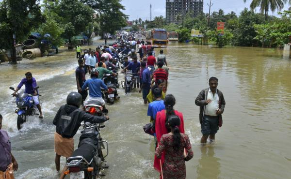 People move past a flooded road in the southern Indian state of Kerala, where monsoon rains have destroyed roads and left hundreds of thousands of people homeless. People move past a flooded road in the southern Indian state of Kerala, where monsoon rains have destroyed roads and left hundreds of thousands of people homeless.