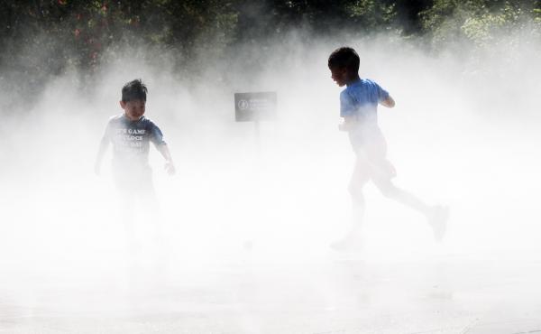Children beat the heat Thursday in a misting pool at a park in Queens as temperatures reach into the 90s in New York City. Children beat the heat Thursday in a misting pool at a park in Queens as temperatures reach into the 90s in New York City.
