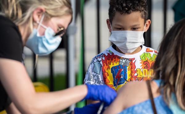 A child watches as a nurse administers a COVID-19 vaccine during a pop-up vaccination event in April at Lynn Family Stadium in Louisville, Ky. A child watches as a nurse administers a COVID-19 vaccine during a pop-up vaccination event in April at Lynn Family Stadium in Louisville, Ky.