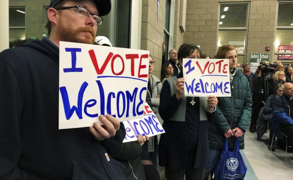 In this Dec. 9. 2019, file photo, residents in support of continued refugee resettlement hold signs at a meeting in Bismarck, N.D. In this Dec. 9. 2019, file photo, residents in support of continued refugee resettlement hold signs at a meeting in Bismarck, N.D.