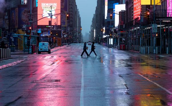A couple wearing masks crosses the almost-deserted Times Square in New York City on Monday. A couple wearing masks crosses the almost-deserted Times Square in New York City on Monday.