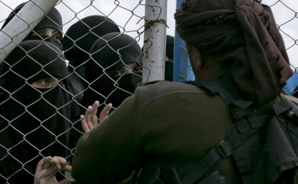 In this March 31, 2019, photo, women speak to guards at the gate that closes off the section for foreign families who lived in the Islamic State's so-called caliphate, at al-Hol camp in Hasakeh province, Syria. In this March 31, 2019, photo, women speak to guards at the gate that closes off the section for foreign families who lived in the Islamic State's so-called caliphate, at al-Hol camp in Hasakeh province, Syria.