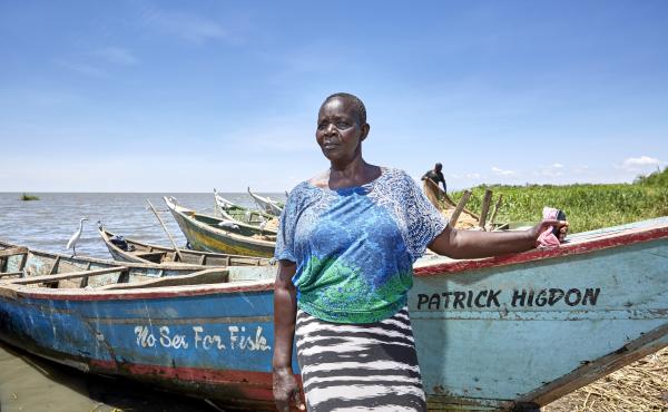 Justine Adhiambo Obura, chairwoman of the No Sex For Fish cooperative in Nduru Beach, Kenya, stands by her fishing boat. Patrick Higdon, whose name is on the boat, works for the charity World Connect, which gave the group a grant to provide boats for some Justine Adhiambo Obura, chairwoman of the No Sex For Fish cooperative in Nduru Beach, Kenya, stands by her fishing boat. Patrick Higdon, whose name is on the boat, works for the charity World Connect, which gave the group a grant to provide boats for some