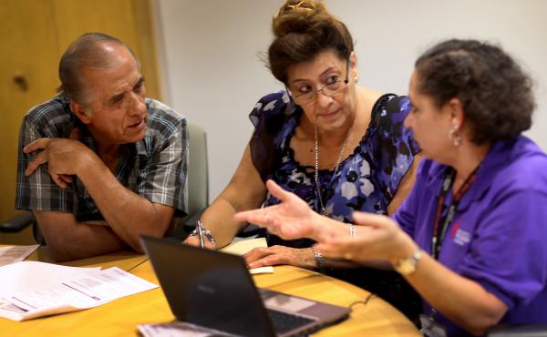 Affordable Care Act navigator Nini Hadwen (right) helped Jorge Hernandez (left) and Marta Aguirre find a plan on the health insurance exchange in Miami in 2013. Today, with fewer navigators, much of that counseling is done by phone instead of in person. Affordable Care Act navigator Nini Hadwen (right) helped Jorge Hernandez (left) and Marta Aguirre find a plan on the health insurance exchange in Miami in 2013. Today, with fewer navigators, much of that counseling is done by phone instead of in person.