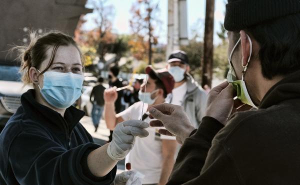 A man is handed a swab for a rapid test as people line up for coronavirus testing at a gas station in the Reseda section of Los Angeles on Sunday. A man is handed a swab for a rapid test as people line up for coronavirus testing at a gas station in the Reseda section of Los Angeles on Sunday.