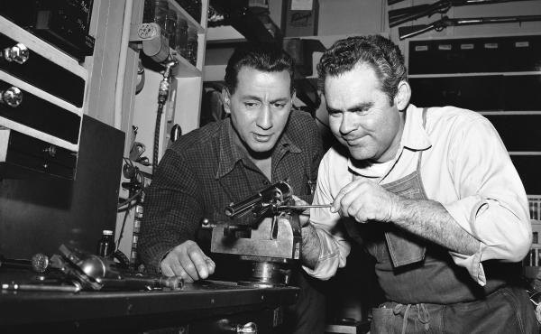 In this photo from a Hollywood studio gun department in 1958, Rodd Redwing (left) checks the final adjustment that Bob Lane is making on a six-gun. Redwing is an actor and a teacher of western gun handling. Lane is one of the men who repair and service th In this photo from a Hollywood studio gun department in 1958, Rodd Redwing (left) checks the final adjustment that Bob Lane is making on a six-gun. Redwing is an actor and a teacher of western gun handling. Lane is one of the men who repair and service th