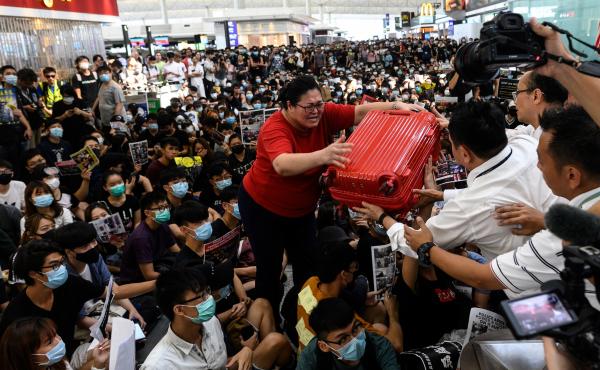 A tourist gives her luggage to security guards as she tries to enter the departures gate during another demonstration by pro-democracy protesters at Hong Kong International Airport on Tuesday. A tourist gives her luggage to security guards as she tries to enter the departures gate during another demonstration by pro-democracy protesters at Hong Kong International Airport on Tuesday.
