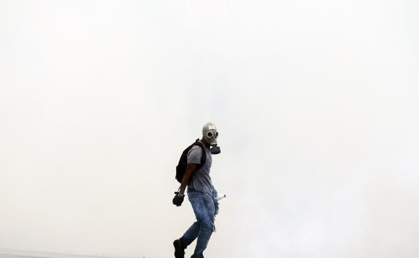 A protester stares down riot police behind his gas mask, during demonstrations against Venezuelan President Nicolas Maduro in Caracas on Thursday. A protester stares down riot police behind his gas mask, during demonstrations against Venezuelan President Nicolas Maduro in Caracas on Thursday.