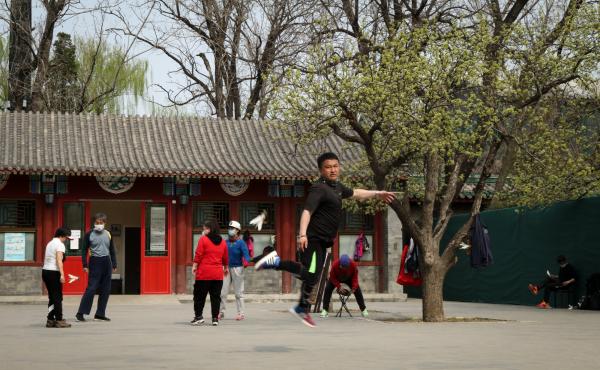 A skilled player of jianzi, or the Chinese equivalent of Hackey Sack, jumps to pass the feathered toy to the next participant. A skilled player of jianzi, or the Chinese equivalent of Hackey Sack, jumps to pass the feathered toy to the next participant.