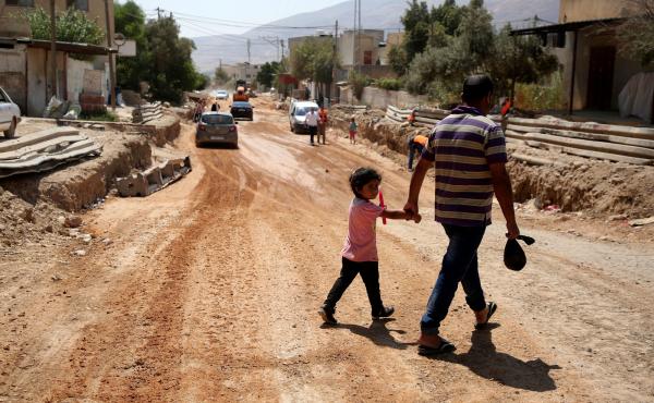 A father and his daughter cross a street under renovations as part of a U.S. aid grant in the village of al-Badhan, north of Nablus in Israeli occupied West Bank in August 2018. A father and his daughter cross a street under renovations as part of a U.S. aid grant in the village of al-Badhan, north of Nablus in Israeli occupied West Bank in August 2018.