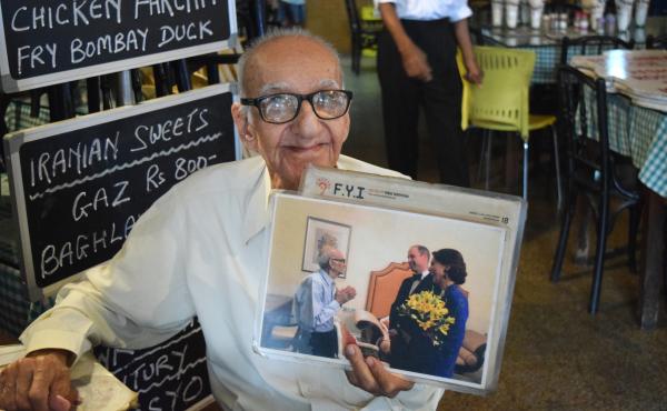 Boman Kohinoor, 97, has spent the past eight decades committed to his beloved Britannia & Co., one of Mumbai's last Parsi cafes. Here, he proudly holds up a photo of himself with two members of the British royal family: the Duke and Duchess of Cambridge, Boman Kohinoor, 97, has spent the past eight decades committed to his beloved Britannia & Co., one of Mumbai's last Parsi cafes. Here, he proudly holds up a photo of himself with two members of the British royal family: the Duke and Duchess of Cambridge,