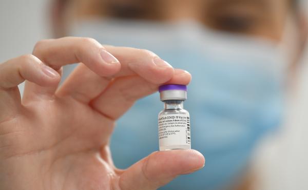 A staff member poses with a vial of Pfizer-BioNTech COVID-19 vaccine at a vaccination health center. A staff member poses with a vial of Pfizer-BioNTech COVID-19 vaccine at a vaccination health center.
