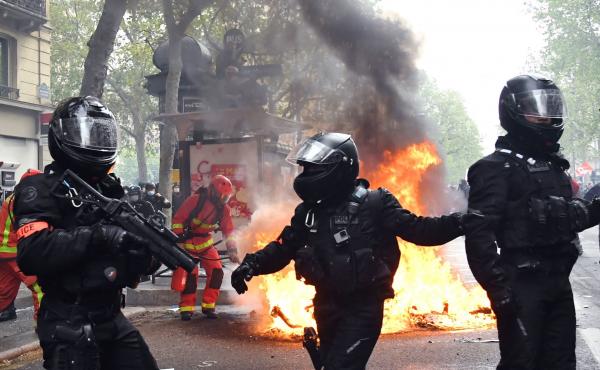 Police officers walk near a fire burning in the street during May Day protests in Paris on Saturday. Police officers walk near a fire burning in the street during May Day protests in Paris on Saturday.