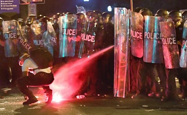 An anti-racism protester near Lafayette Square in Washington, D.C., in May is tear-gassed as he attempts to retrieve a flare thrown at police. An anti-racism protester near Lafayette Square in Washington, D.C., in May is tear-gassed as he attempts to retrieve a flare thrown at police.