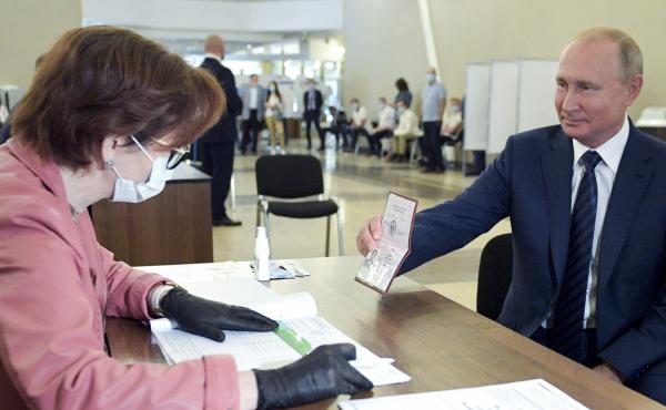 Russian President Vladimir Putin shows his passport to a member of an election commission as he arrives to take part in voting at a polling station in Moscow on Wednesday. Russian President Vladimir Putin shows his passport to a member of an election commission as he arrives to take part in voting at a polling station in Moscow on Wednesday.