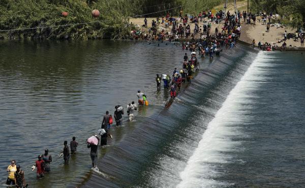 In this Sept. 18, 2021, file photo Haitian migrants use a dam to cross into the United States from Mexico in Del Rio, Texas. In this Sept. 18, 2021, file photo Haitian migrants use a dam to cross into the United States from Mexico in Del Rio, Texas.