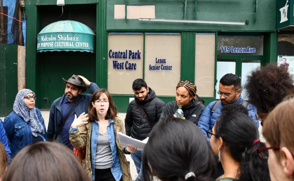 Tour participants listen to guide Katie Merriman (center) outside the Malcolm Shabaaz Mosque as she speaks about the influence of Malcolm X on the Harlem community. Tour participants listen to guide Katie Merriman (center) outside the Malcolm Shabaaz Mosque as she speaks about the influence of Malcolm X on the Harlem community.