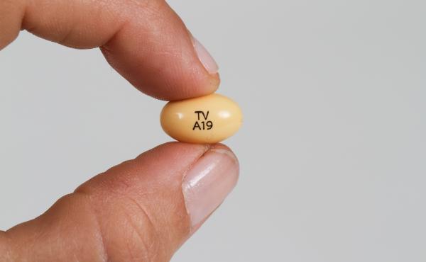 A progesterone pill held between a woman's fingers. A progesterone pill held between a woman's fingers.