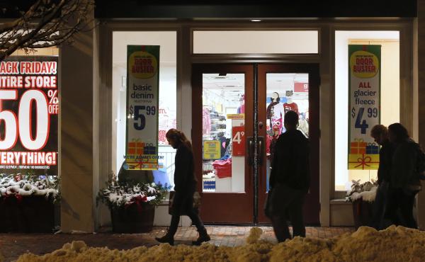 Shoppers in Freeport, Maine, pass by store windows advertising Black Friday deals after the stores opened their doors at midnight. Shoppers in Freeport, Maine, pass by store windows advertising Black Friday deals after the stores opened their doors at midnight.