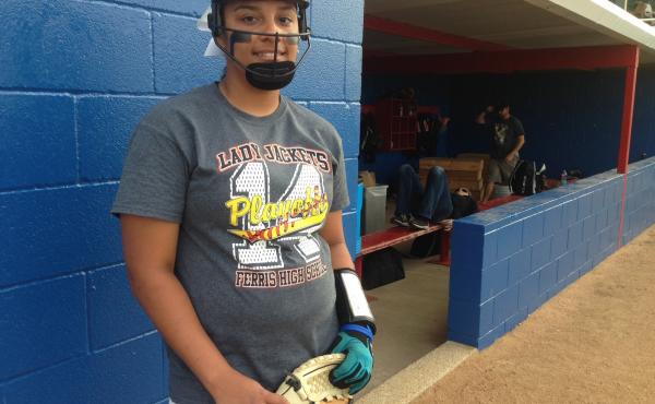 Ferris High School softball player Kylee Fowler stands beside the dugout, face mask on and ready. Ferris High School softball player Kylee Fowler stands beside the dugout, face mask on and ready.
