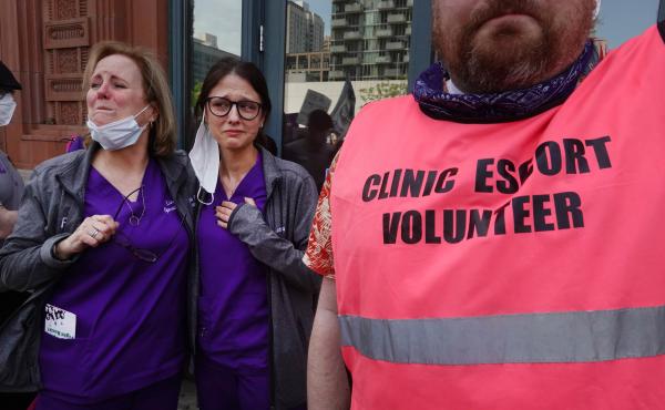 Workers at a family planning health center get emotional as thousands of abortion rights advocates march past their clinic on their way into downtown Chicago on May 14, 2022. Workers at a family planning health center get emotional as thousands of abortion rights advocates march past their clinic on their way into downtown Chicago on May 14, 2022.