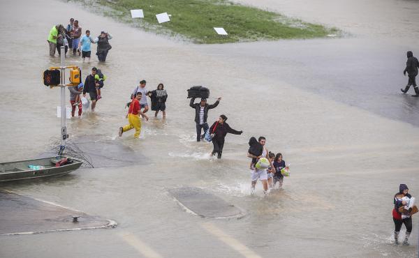 People walk down a flooded street as they evacuate their homes in Houston, Texas, on Monday. People walk down a flooded street as they evacuate their homes in Houston, Texas, on Monday.