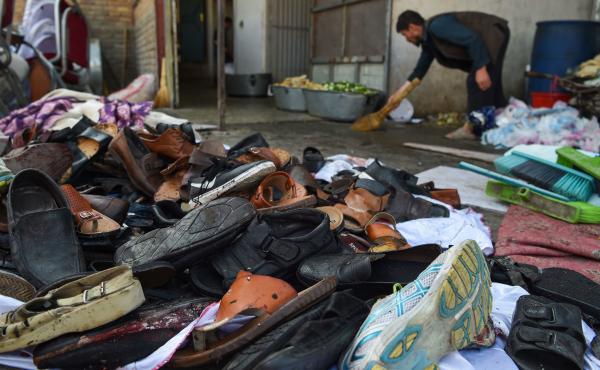 A man cleans an area next to a pile of victims' shoes outside a wedding hall after a deadly suicide bomb blast on Saturday night in Kabul, Afghanistan. A man cleans an area next to a pile of victims' shoes outside a wedding hall after a deadly suicide bomb blast on Saturday night in Kabul, Afghanistan.